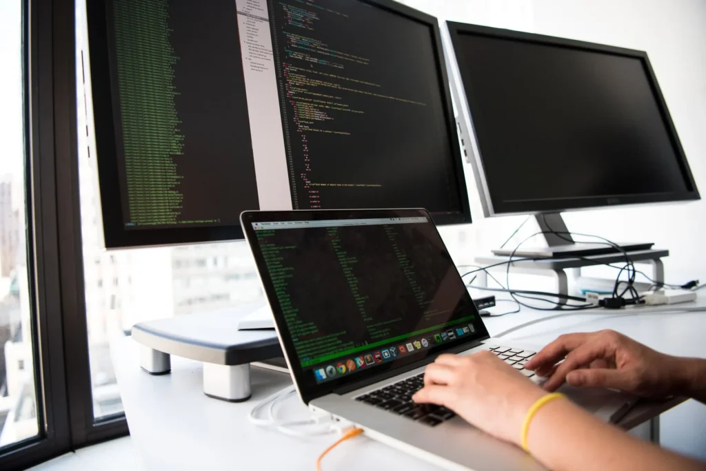Programista pracuje przy komputerze z dwoma monitorami